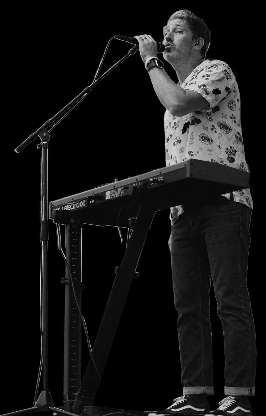 Chris singing on stage behind his keyboard